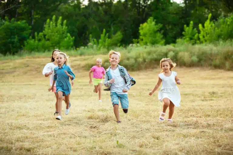 Kids, children running on meadow in summer's sunlight