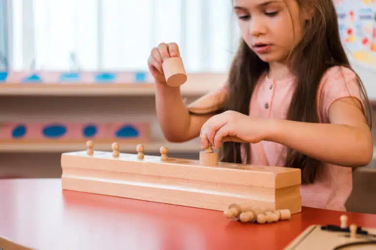 Child playing wooden educational game in montessori school